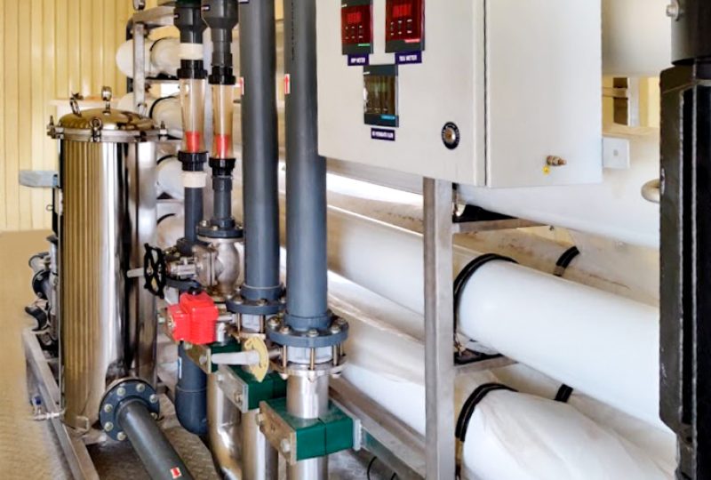 Close-up of containarised desalination system with filtration units, piping, and pressure gauges